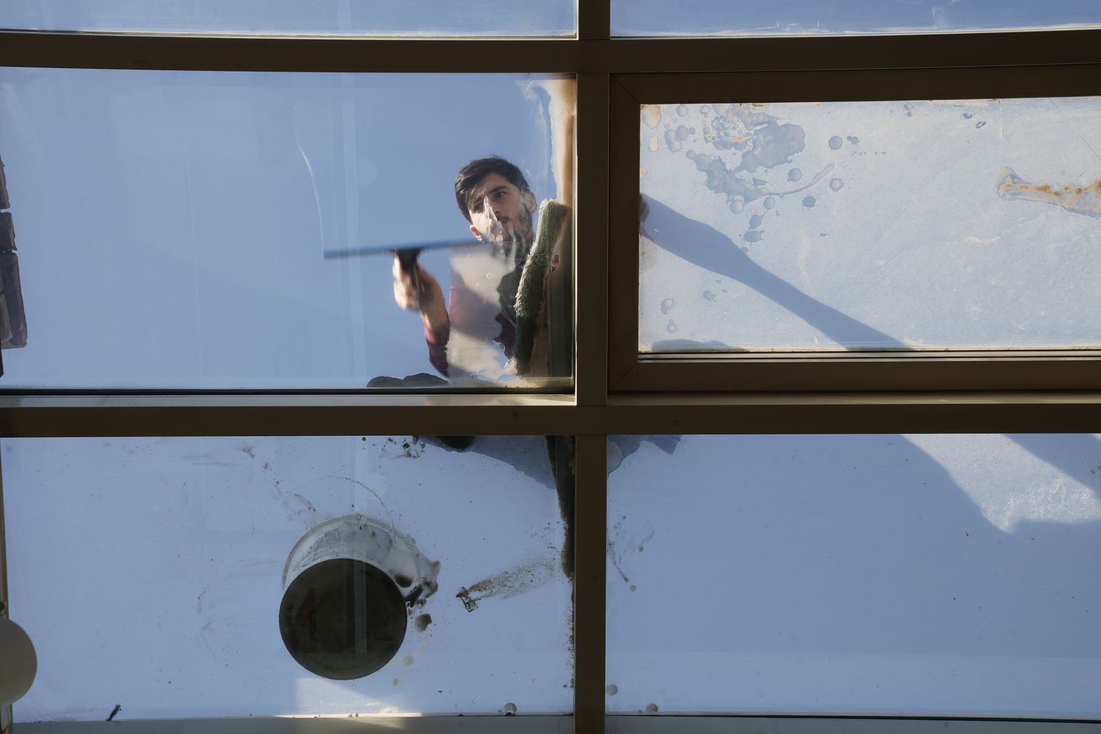 A window cleaner working exterior glass with a hand tool